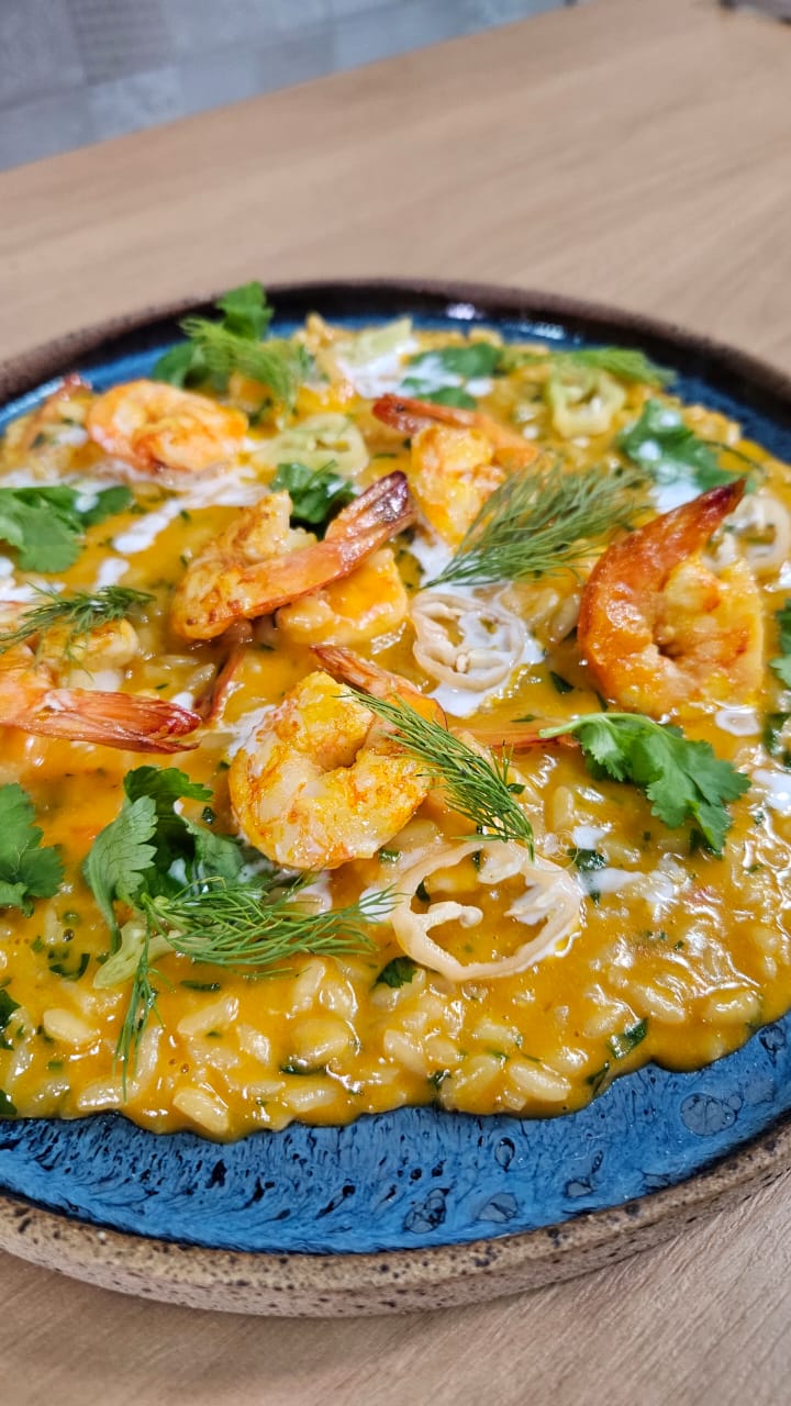 Risotto cremoso sendo finalizado em panela de cobre, vapor subindo